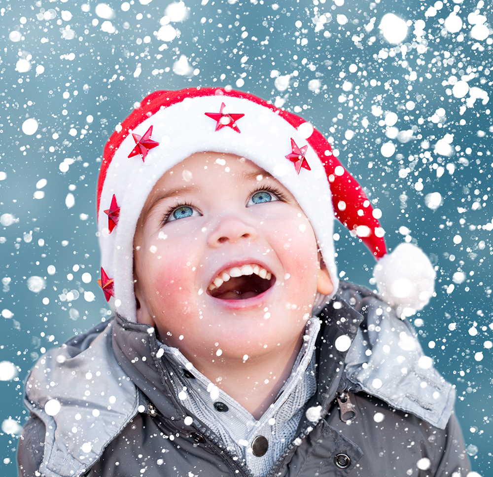 Happy child wearing Christmas hat looking at snow